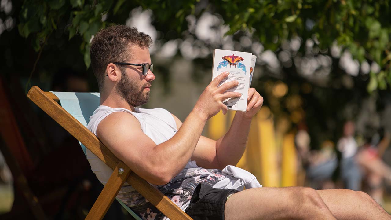 Person reading a book sat in a deck chair at Hay Festival