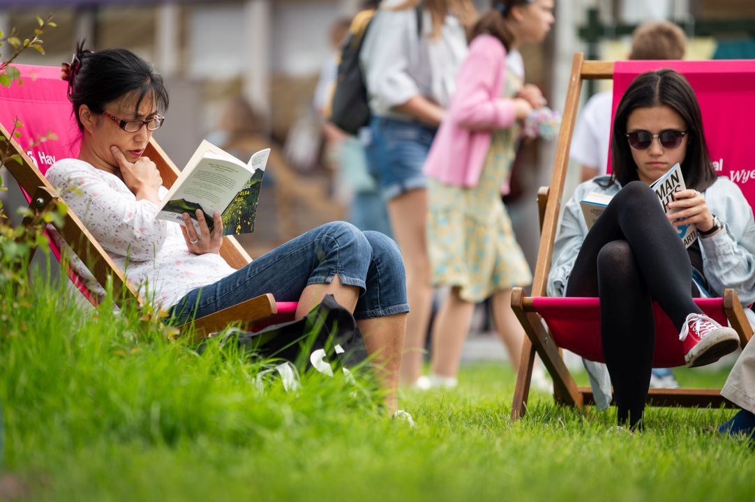 Two readers sitting on deck chairs outside at Hay Festival 2024